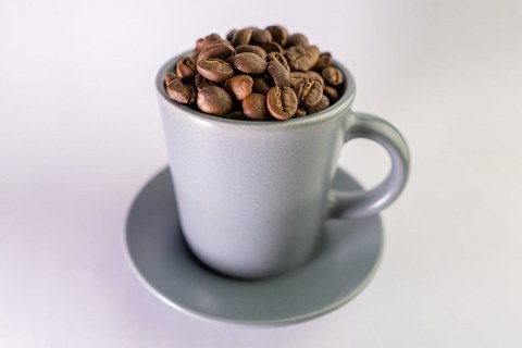 Cup filled with roasted coffee beans Cup filled with roasted coffee beans